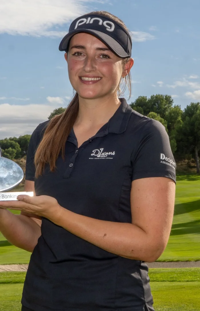Jae Bowers holding a trophy, with sponsor logos on the chest and left sleeve of her polo