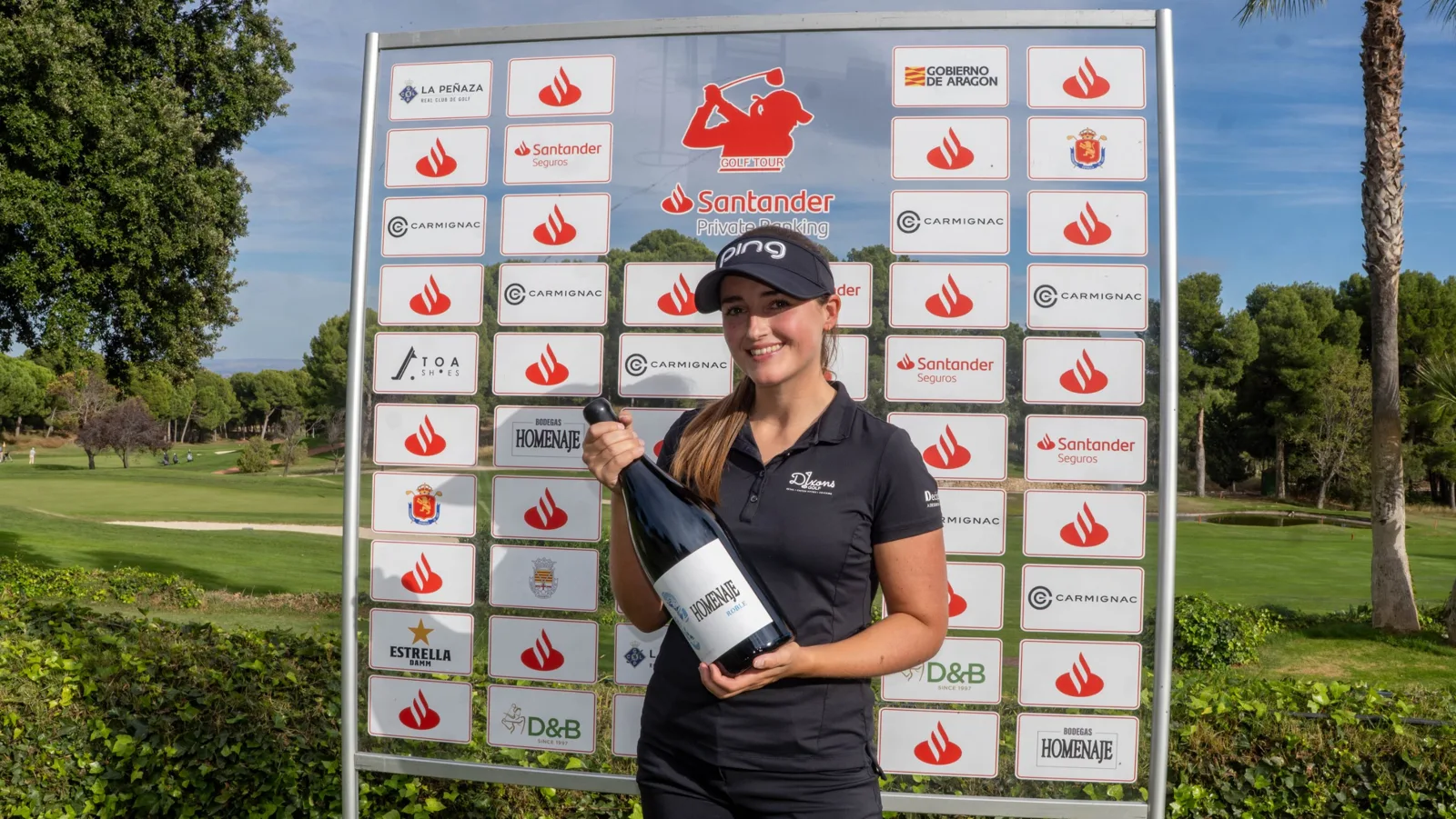 Jae Bowers with the winner's prize in front of the Santander Golf Tour sponsor board